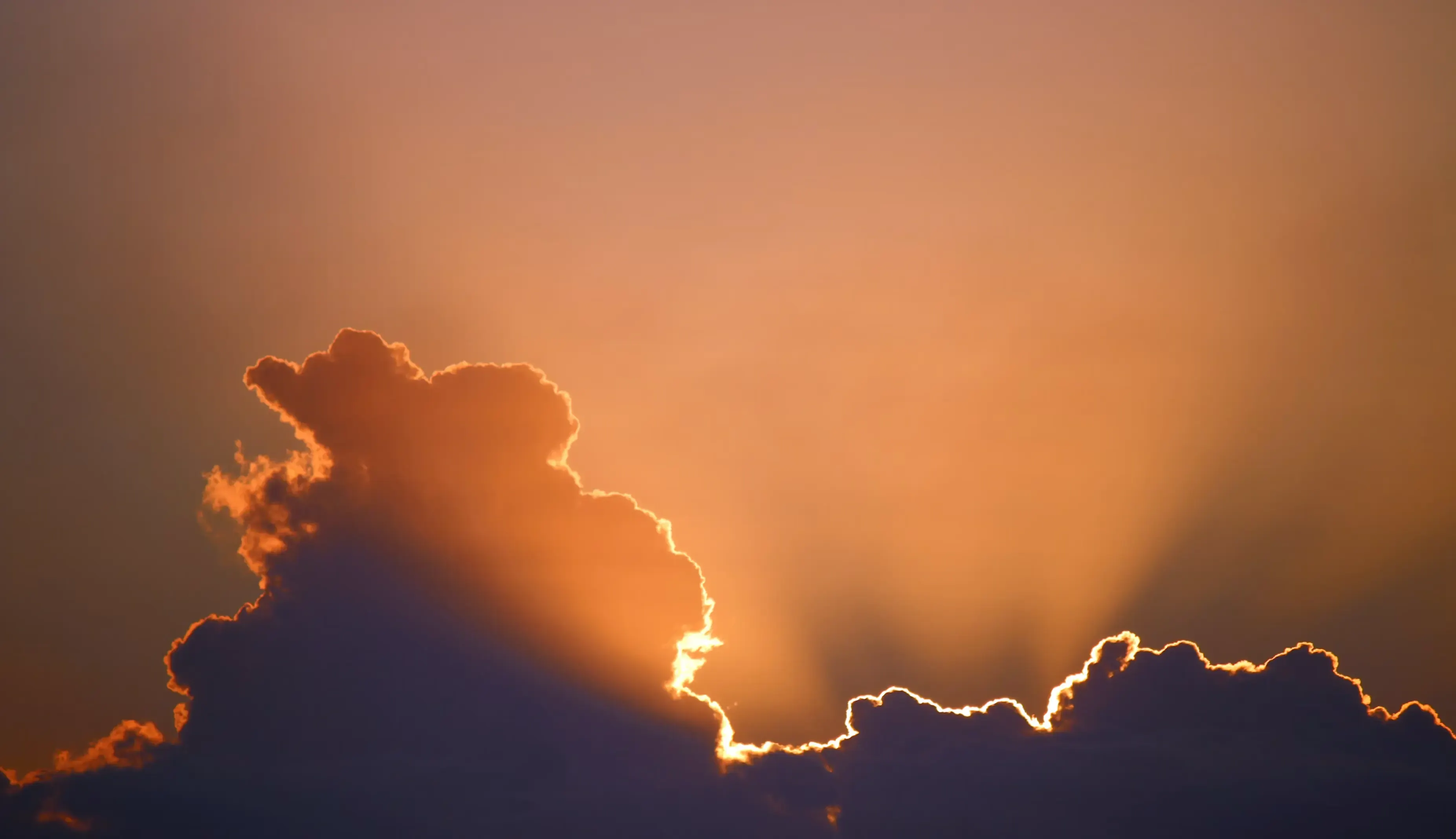 Il sole all'orizzonte sul mare, sotto un cielo acceso di rosso e arancione.